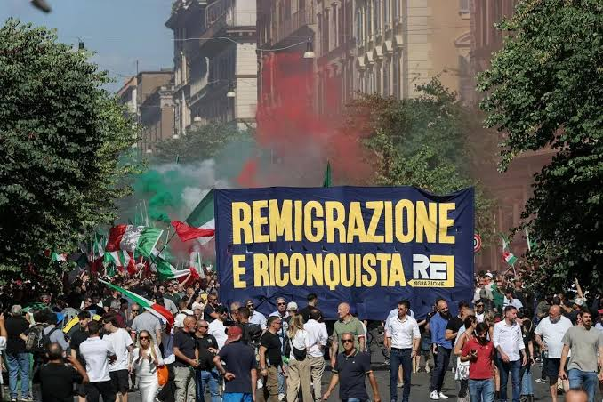 Far-right demonstrators marching with a banner during a rally in RomeNote. From "Far-right demo in Italy calls for 'remigration' of foreigners," by F. Fotia / Reuters, 2026, The Straits Times. (straitstimes.com).